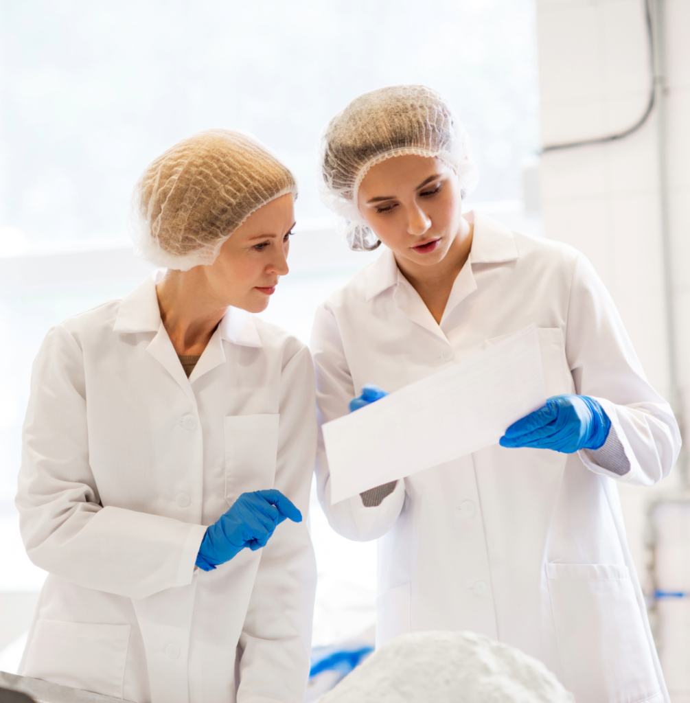 Twee kwaliteitsmedewerkers bespreken een correctieve reiniging na een auditbevinding in de voedingsindustrie.