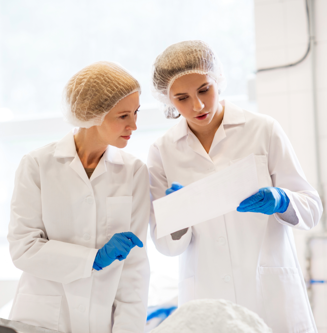 Twee kwaliteitsmedewerkers bespreken een correctieve reiniging na een auditbevinding in de voedingsindustrie.